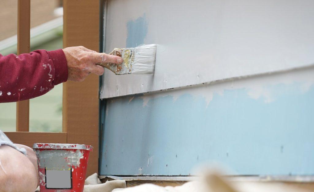 Handyman painting the exterior wall of the house