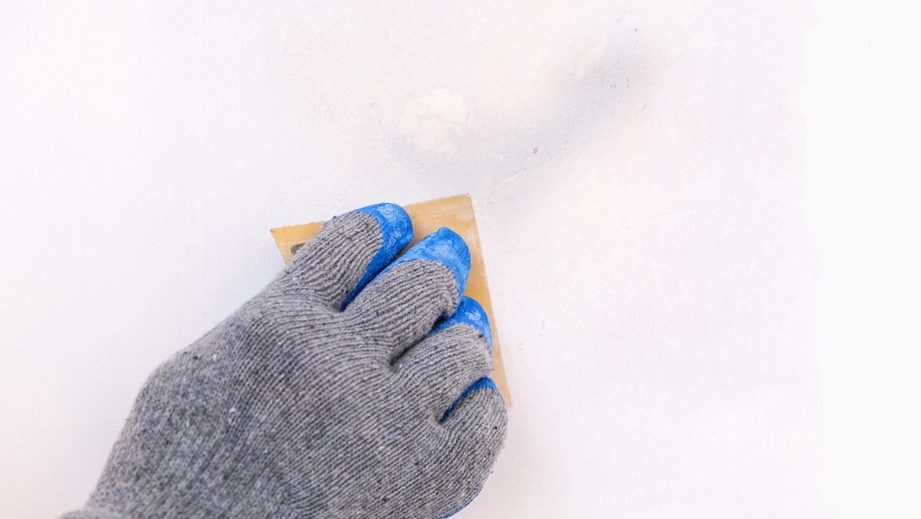 Man cleans old paint on a wooden door with sandpaper