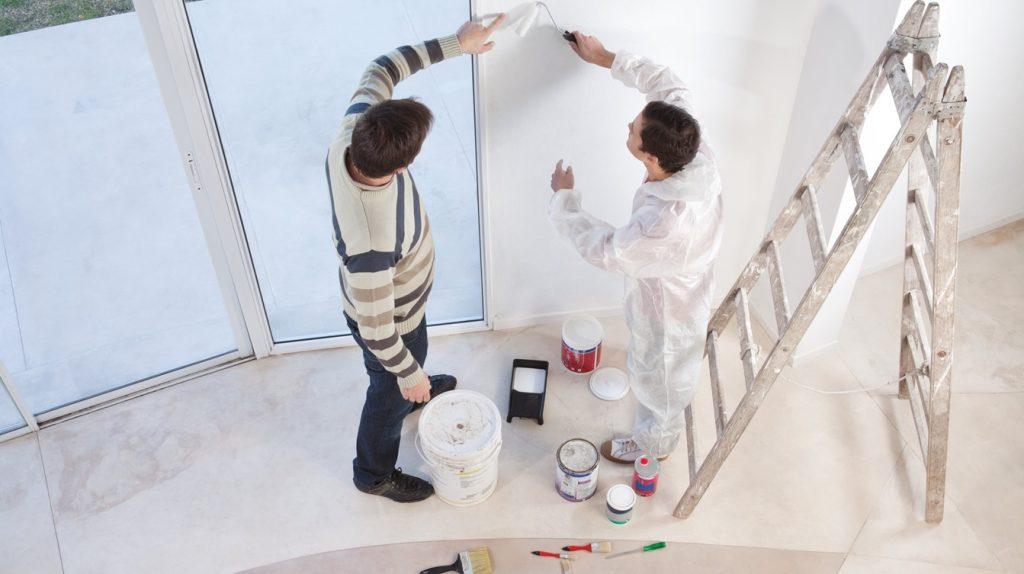 Man showing a spot on the wall to a painter