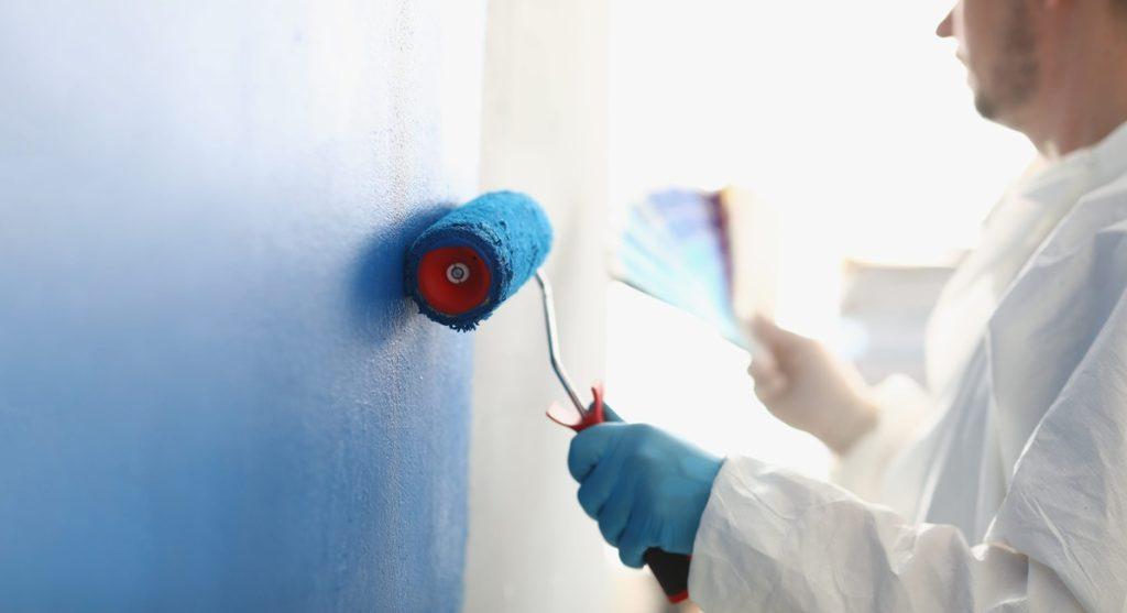 Painting a white wall with a blue roller