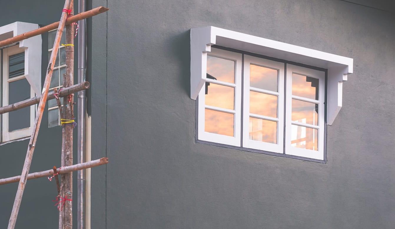 Glass window on gray cement wall of house during renovation work