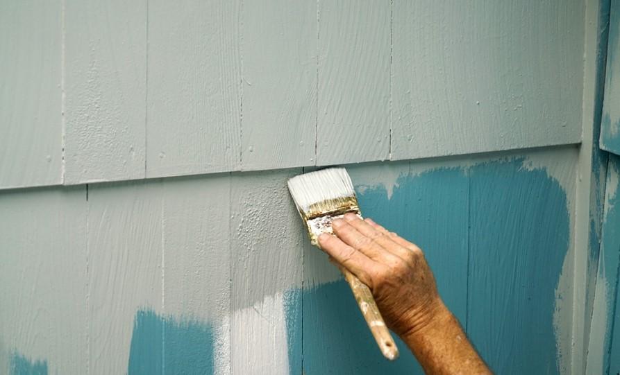 Handyman painting the exterior wall of house