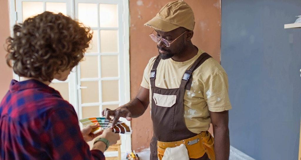 Interior designer discussing paint swatches with a painter in a partially renovated room