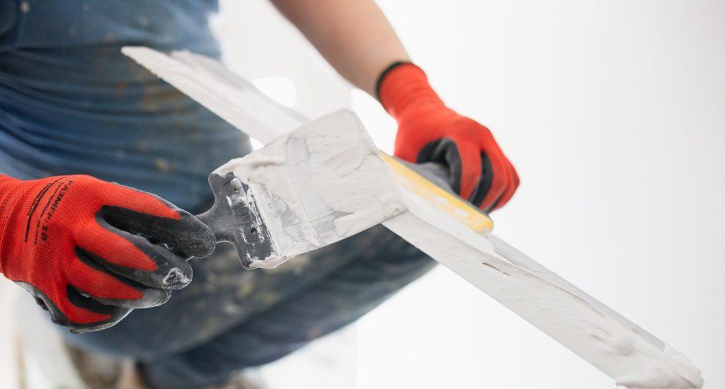 Painter levels the walls with putty using a wide spatula