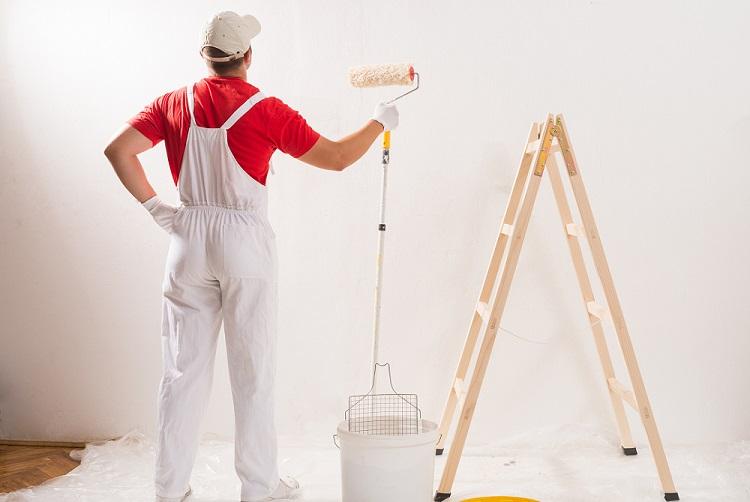 A young man painting wall with roller