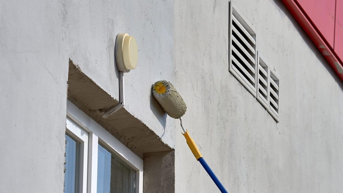 Painting the street wall with a roller with gray paint