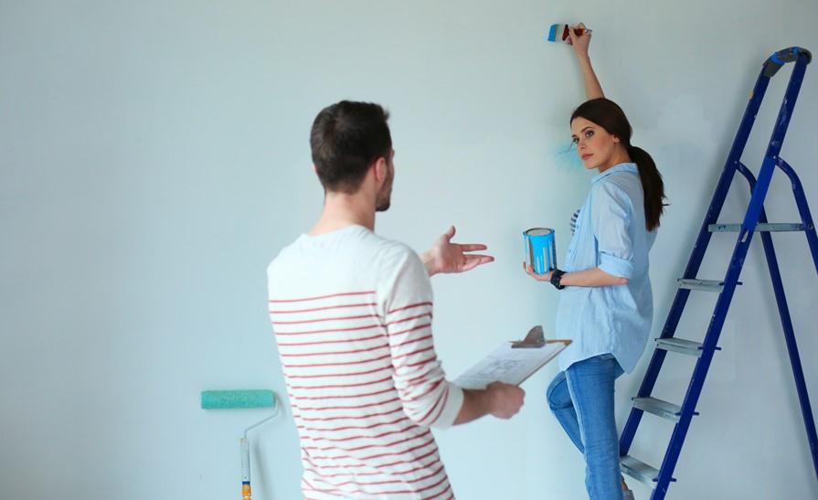 Young couple painting new house interior wall